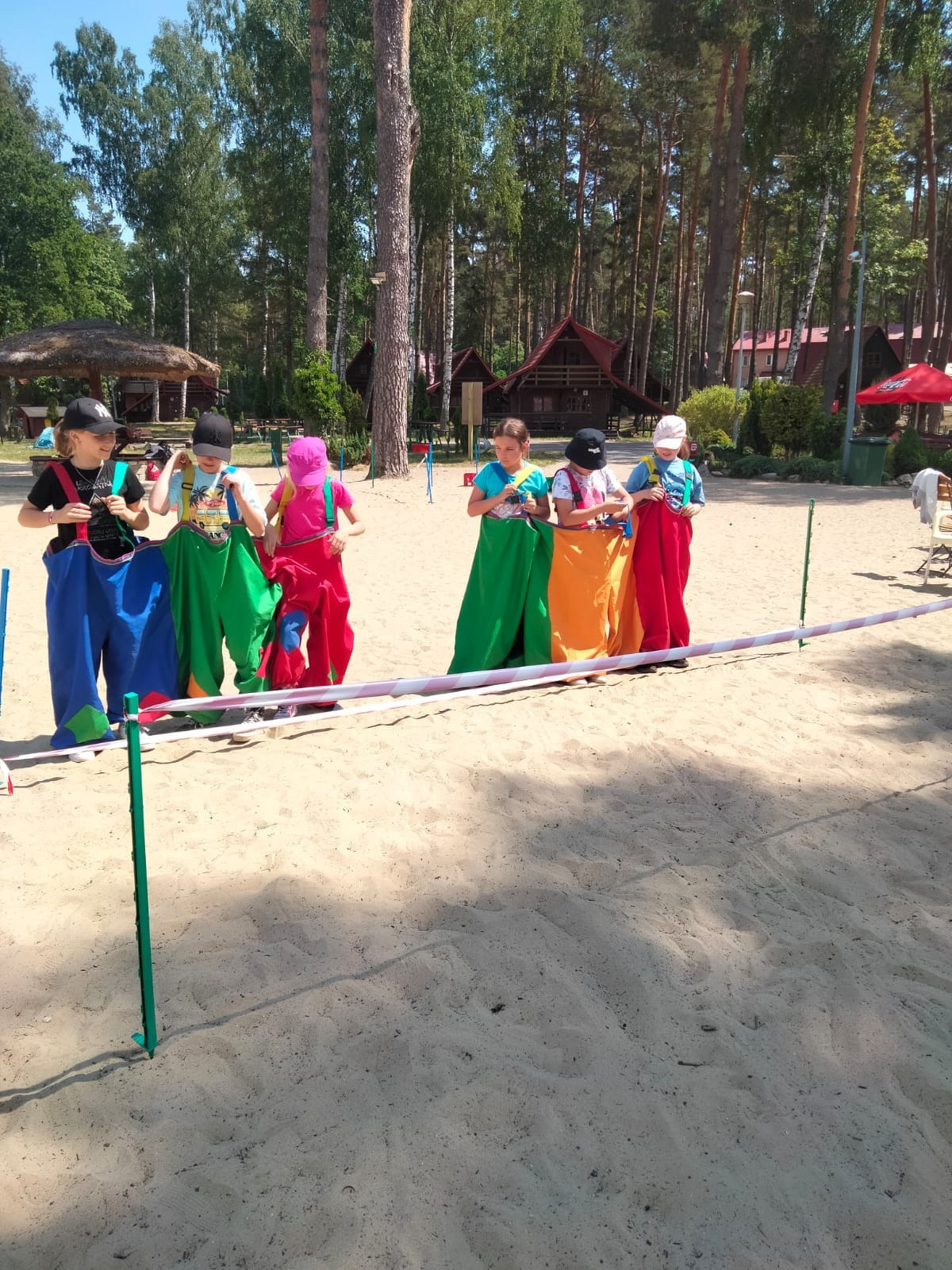 Dzieci biorące udział w zabawie - skoki w kolorowych workach. 
