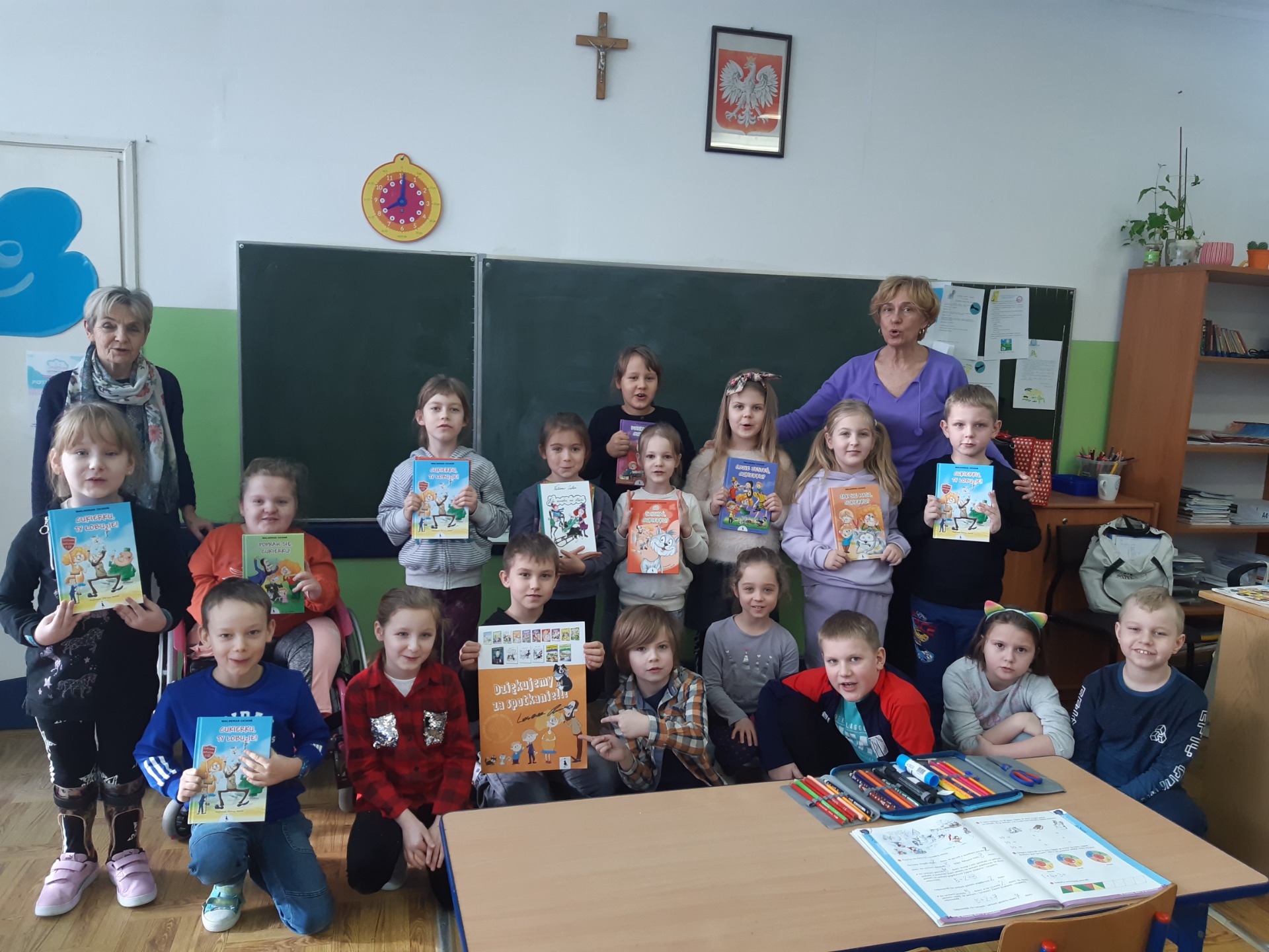 Dzieci z klasy Ie trzymają w rękach zakupione książki z autografem autora p. Waldemara Cichonia. Z  prawej strony wychowawczyni p. Iwona Brzezińska, od lewej nauczyciel bibliotekarz p. Maria Koźlicka.