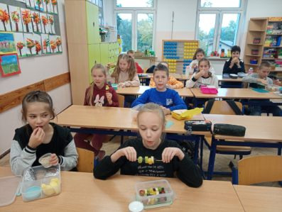 Uczniowie w sali lekcyjnej jedzą zdrowe śniadanie.
