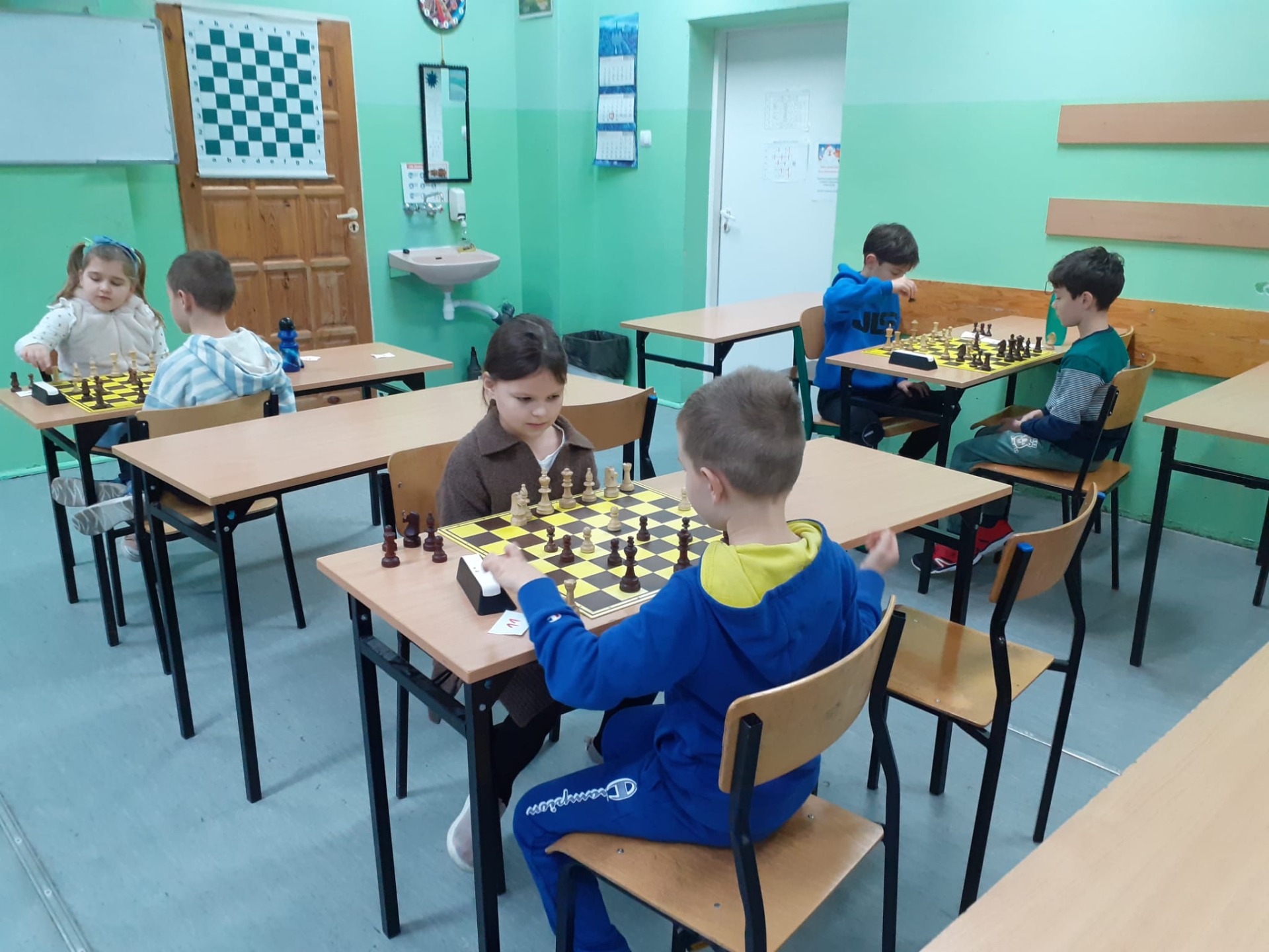Uczniowie grają w szachy w sali szkolnej. 
