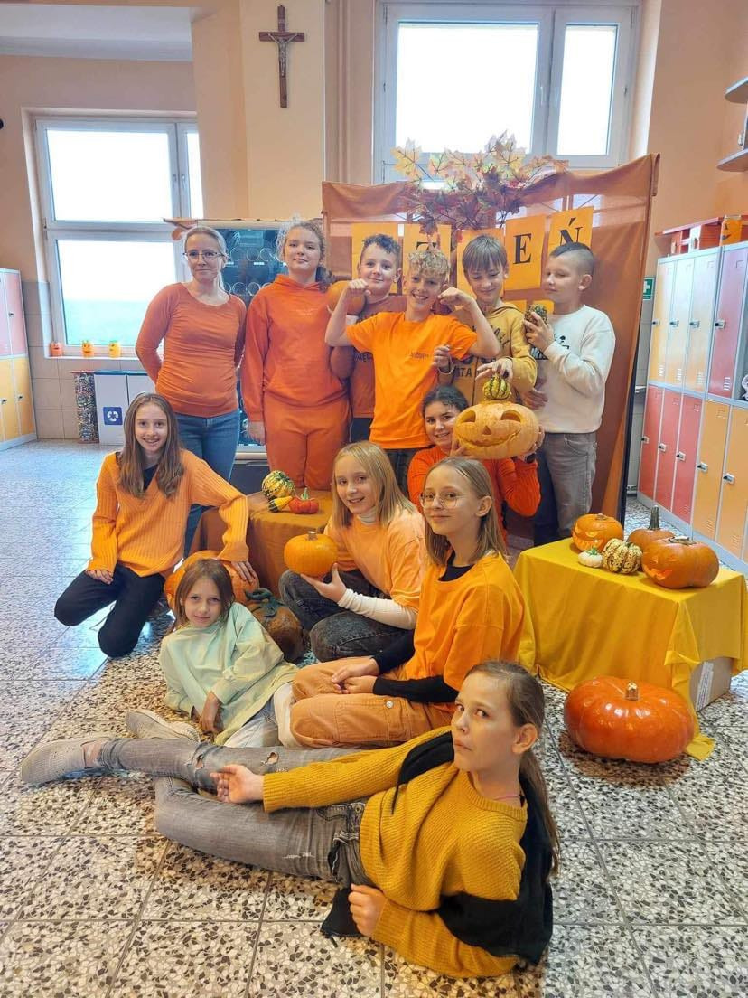 Dzieci ubrane na pomarańczowo pozują razem z organizatorem akcji