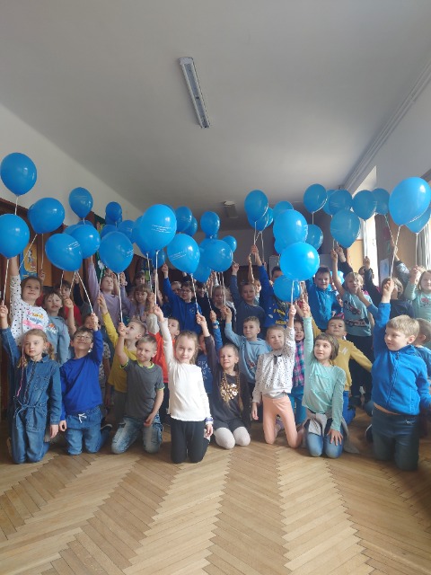 Uczniowie kl .1-3I stoją w grupie, każdy w podniesionej do góry ręce trzyma niebieski balon.