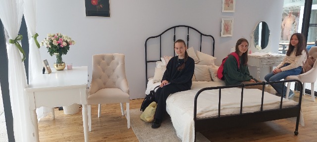 2 uczennice siedzą na łóżku, 1 na fotelu w pokoju Hailie Monet.