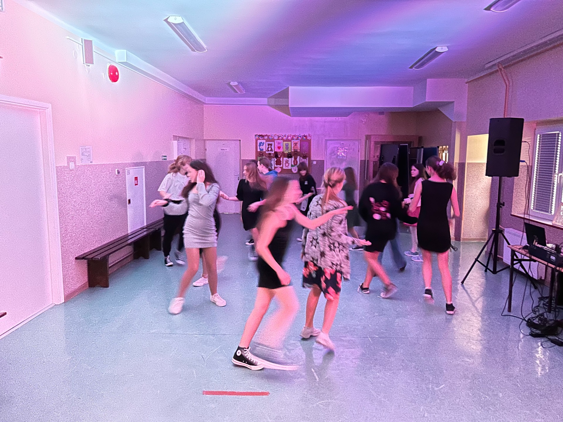Grupa uczniów, chłopców i dziewczynek tańcząca na szkolnym holu podczas zabawy Andrzejkowej. 