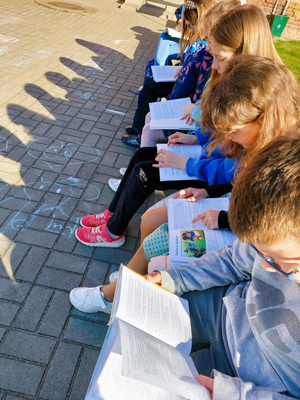 Uczniowie czytają książkę w plenerze