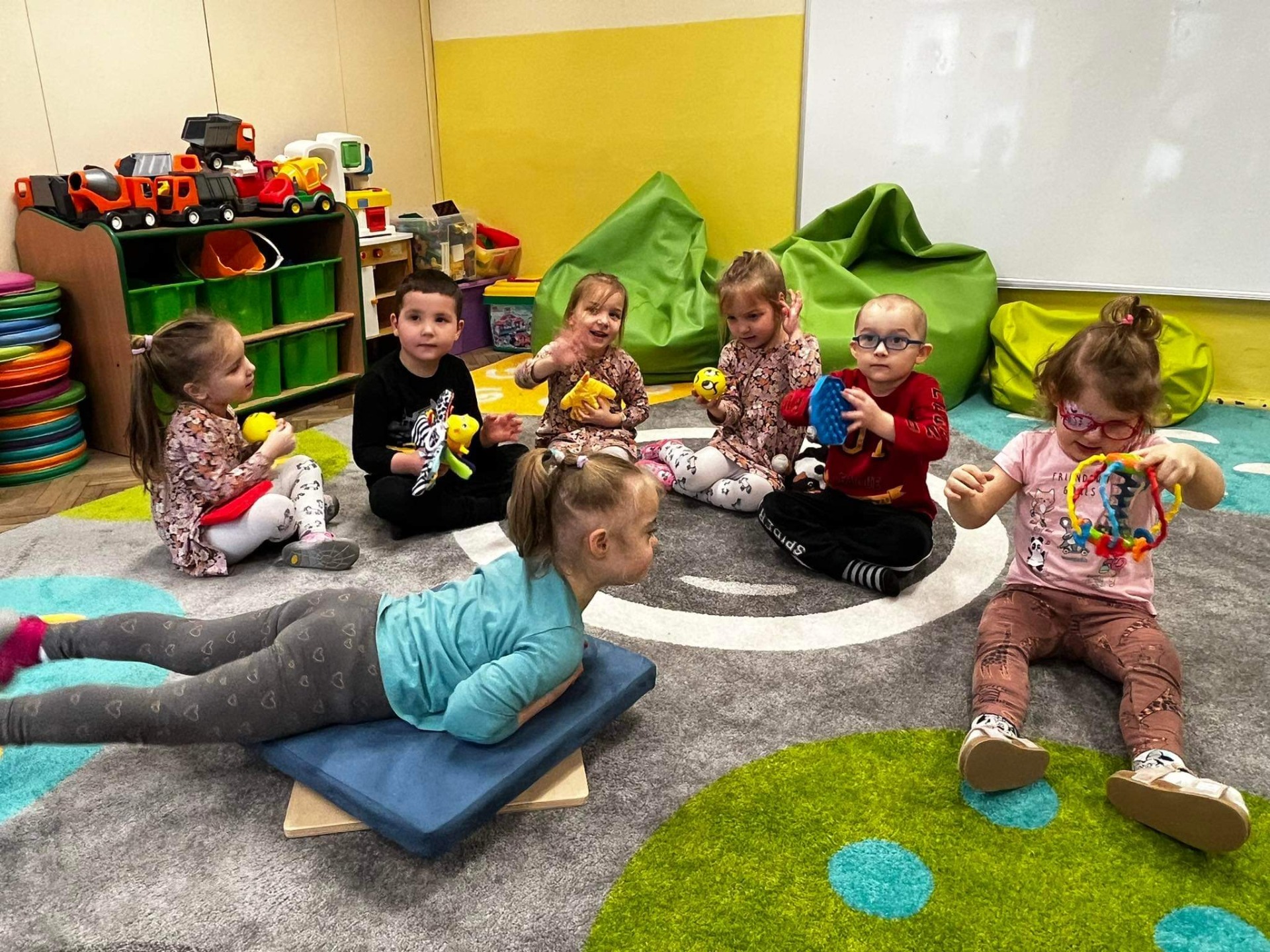 Dzieci bawią się w sali zabawkami sensorycznymi. 