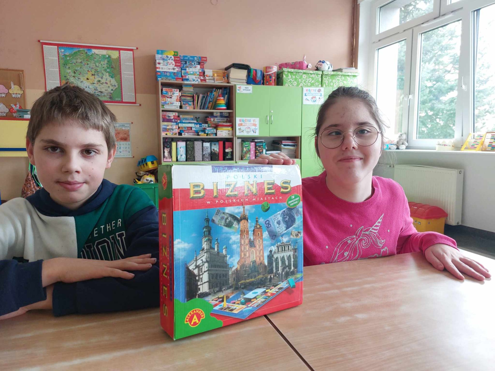 Chłopiec i dziewczynka pozują do zdjęcia z pudełkiem od gry