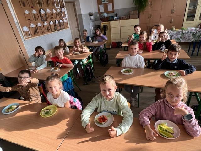16 uczniów siedzi przy stolikach, na których postawione są talerze z przygotowanymi zdrowymi kanapkami.