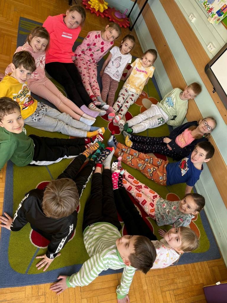 Fotografia przedstawia uczniów prezentujących na stopach kolorowe skarpetki 