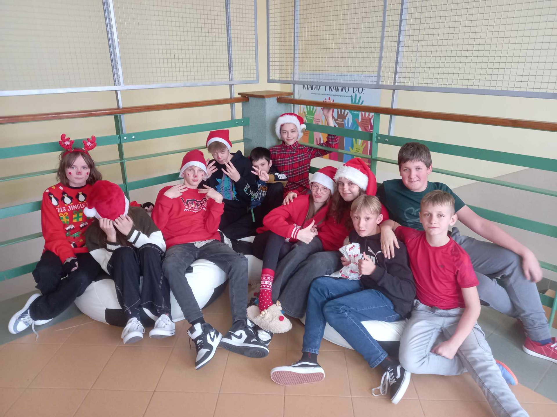 Uczniowie siedzący na korytarzu oczekujący na wizytę Świętego Mikołaja.